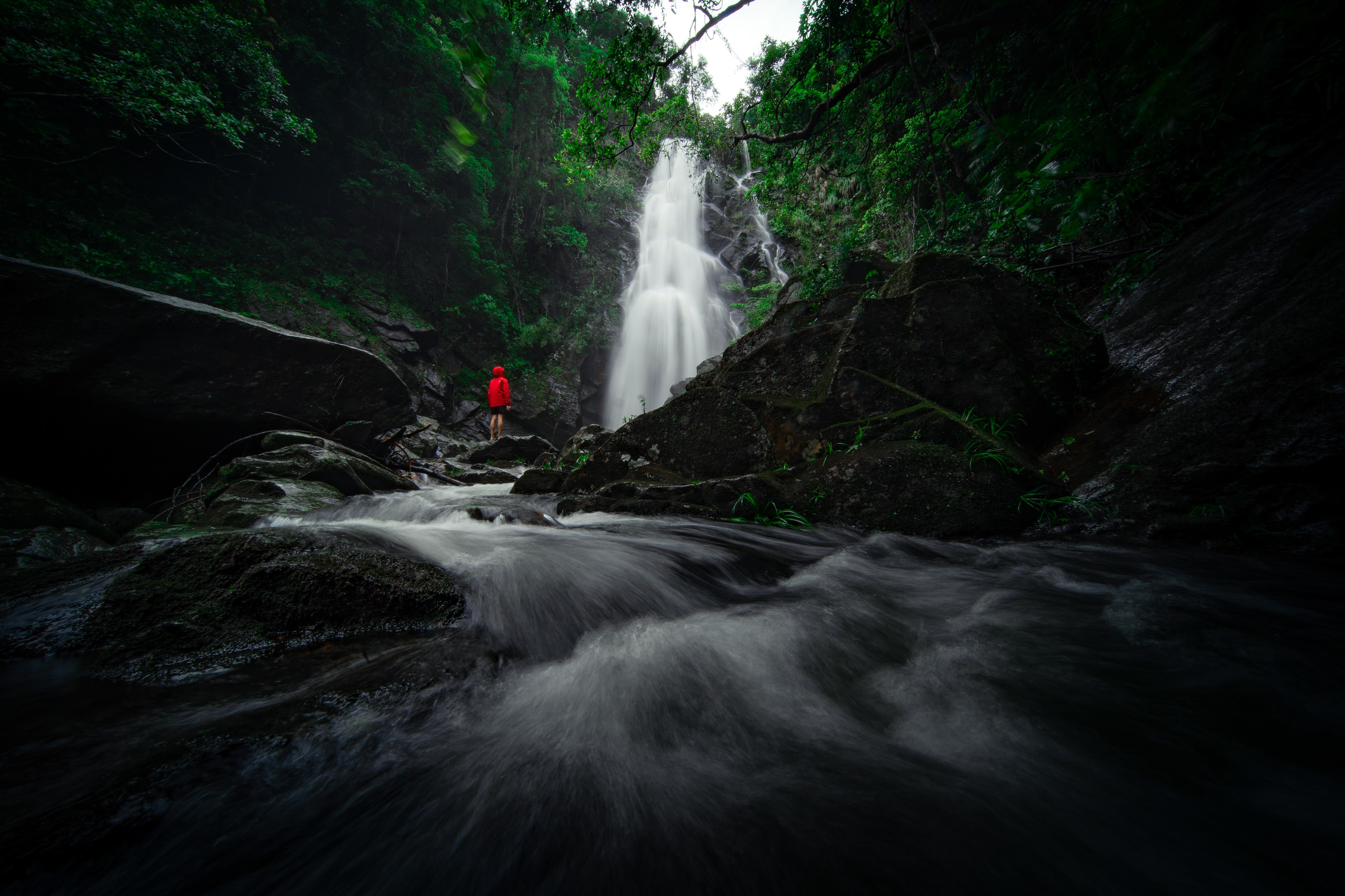 A person stands in front of a magnificent waterfall.